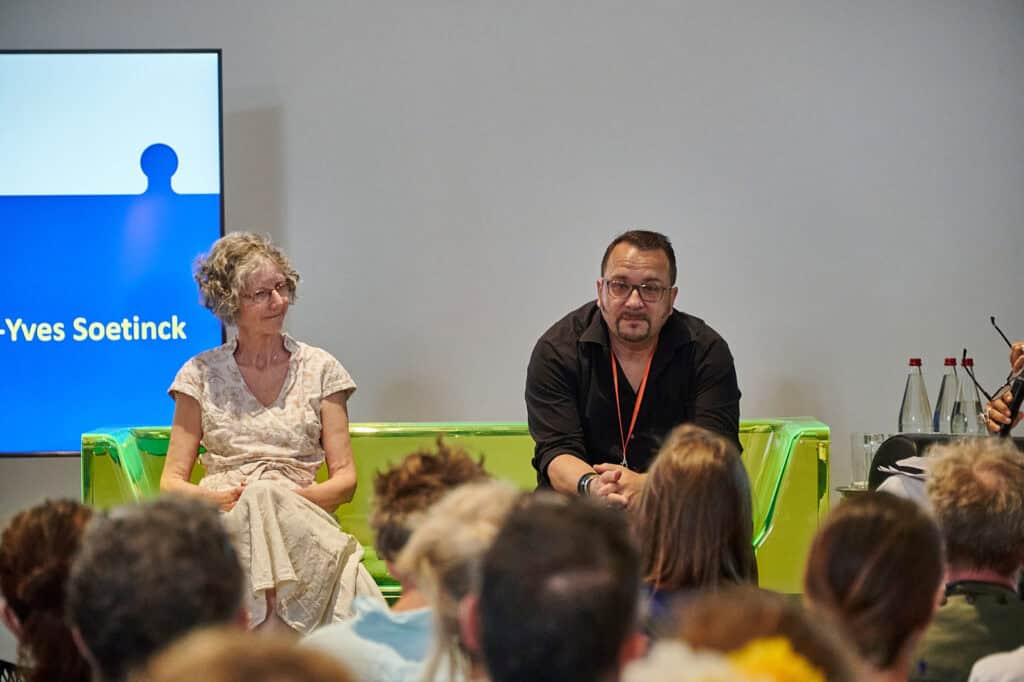 Hélène Foglar (Athéna-Lum) et Jean-Yves Soetinck (L'Acte Lumière) dans le canapé vert des Heureuses Coïncidences HC16, Lézigno, 13 juin 2025. Crédit photo Hugo DaCosta / Association Lézigno.