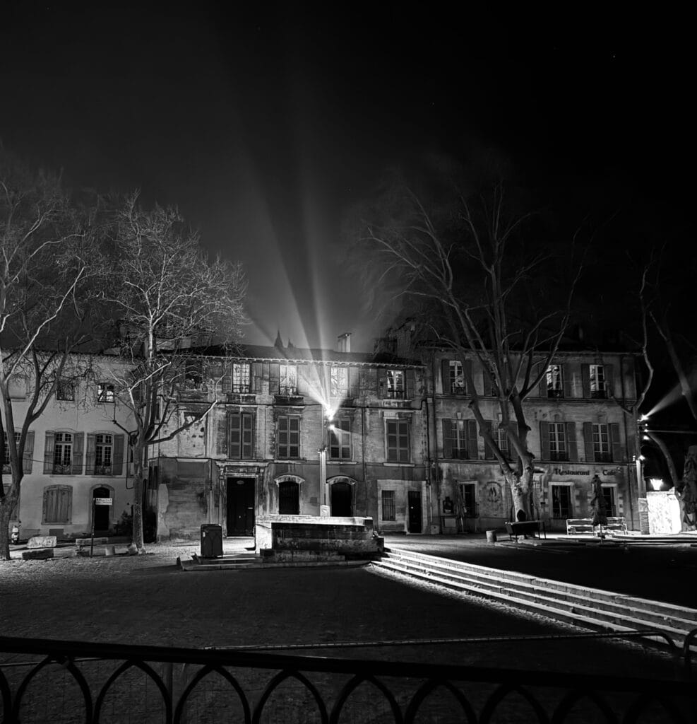 Place du Palais des Papes d'Avignon la nuit, halo lumineux depuis les mats, réglages nocturnes par L'Acte Lumière.