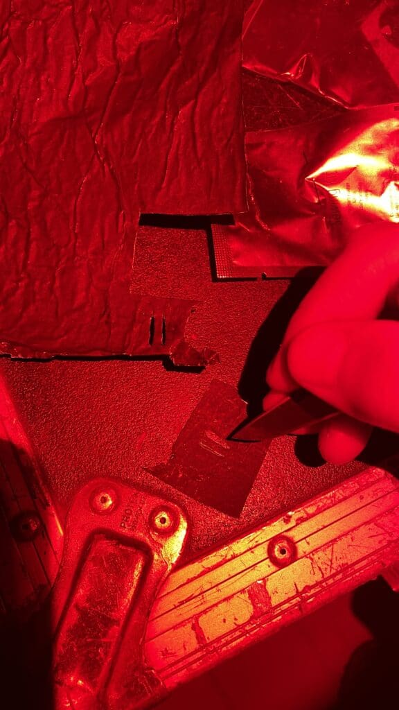 Gros plan sur du black foil découpé au cutter sous éclairage rouge, workshop Going Dark 2024