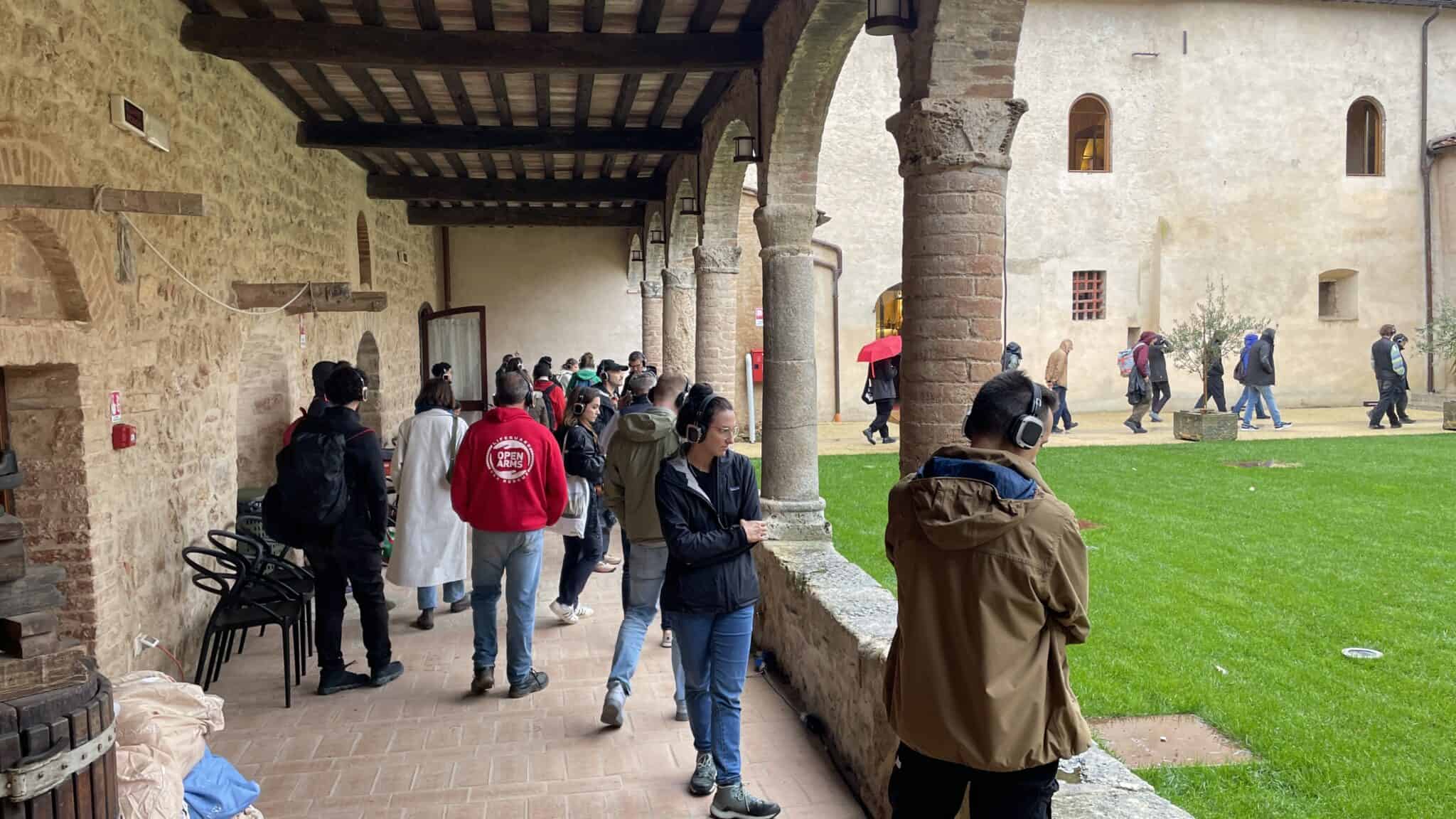 Groupe avec casques audio déambulant dans le cloître de jour, Silent Play Going Dark 2024