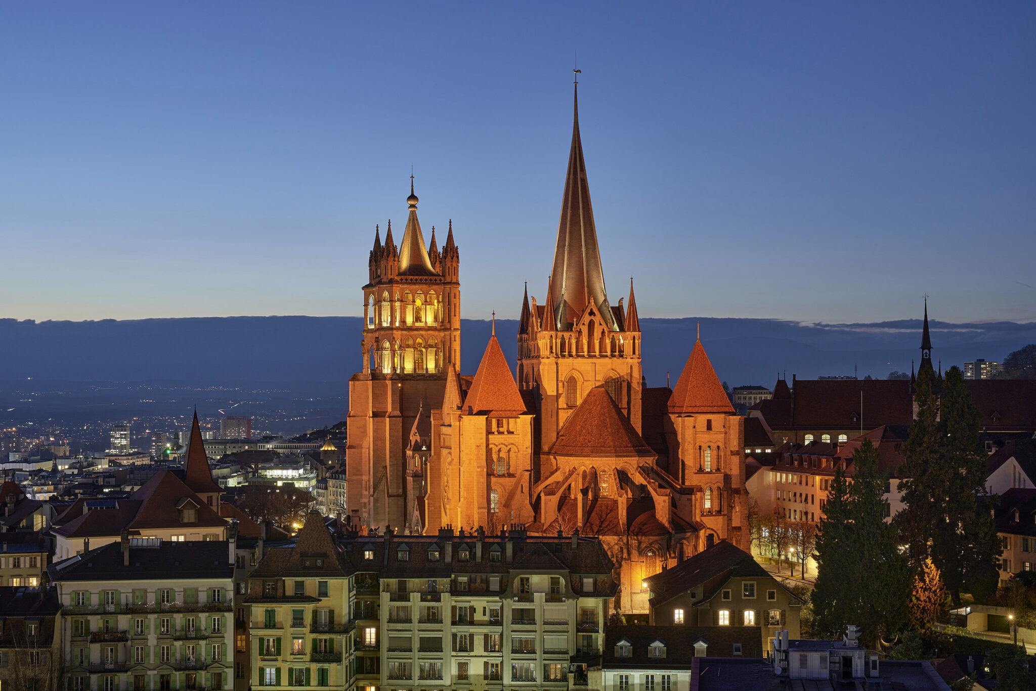 Cathédrale de Lausanne au crépuscule hivernal, voile ambré H1, silhouette sur heure bleue, L'Acte Lumière.